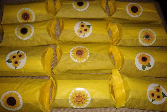 Earrings packaged in yellow wrapping with sunflower stickers featuring Ukraine coat of arms pendant design