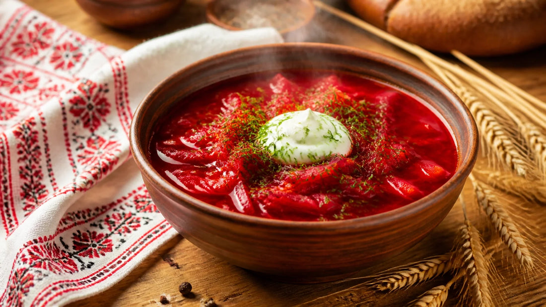 A warm, vibrant bowl of traditional Ukrainian borsch with sour cream and fresh dill on a rustic wooden table