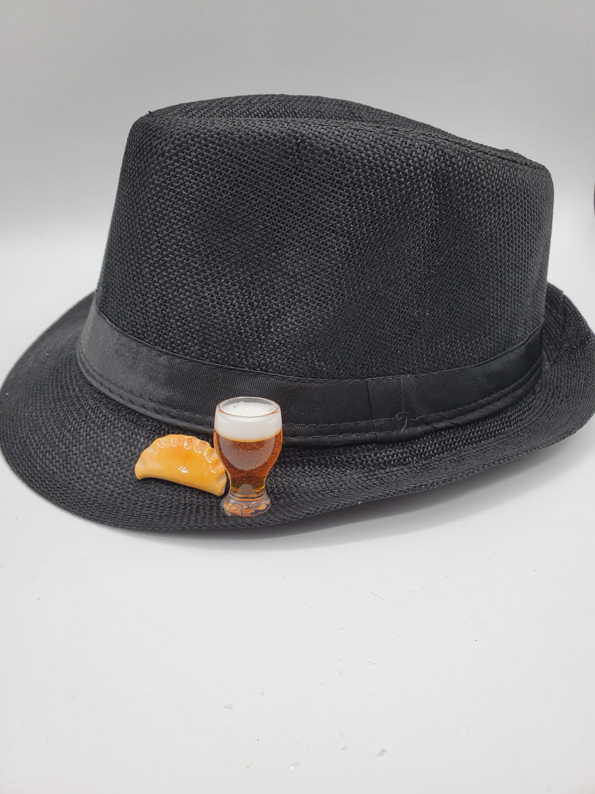 Black fedora pierogi hat by Pierogi Gifts featuring a textured weave and decorative pierogi and beer pins