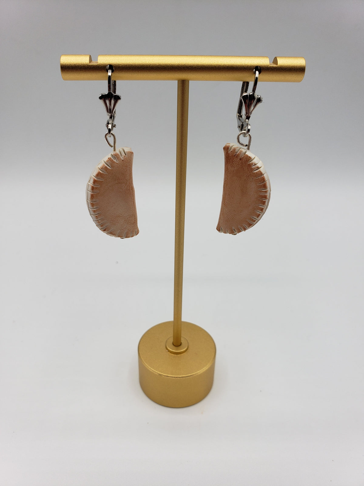 Pierogi shaped earrings displayed on a gold stand, unique jewelry from Pierogi Gifts