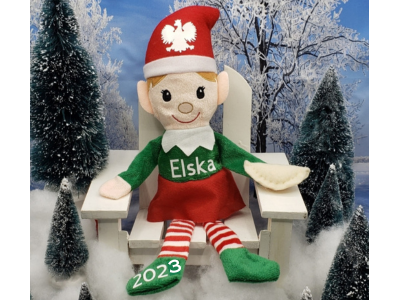 Elska The Polish Elf Doll Plush sitting on white chair with red hat and green outfit surrounded by snowy trees