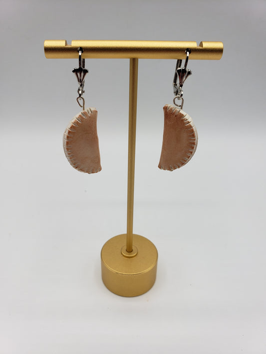 Pierogi shaped earrings displayed on a gold stand, unique jewelry from Pierogi Gifts